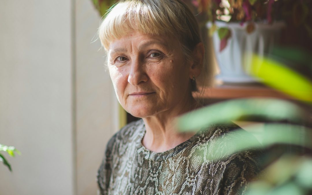 Thoughtful middle-aged woman standing by a window, reflecting on perimenopause symptoms and hormonal changes