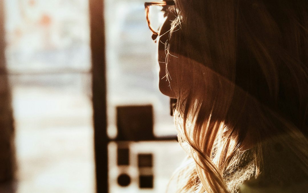 Woman looking thoughtfully out a sunlit window, reflecting the mental clarity many women seek during perimenopause