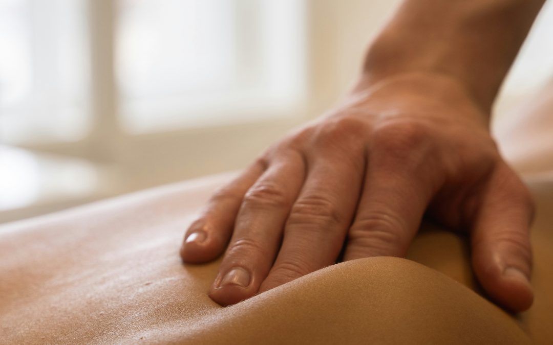Massage therapist's hands applying firm pressure to a client's upper back and shoulder during a massage session