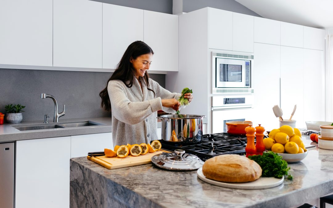Woman preparing fresh vegetables and citrus in a bright kitchen, representing nutrition-focused naturopathic support for PCOS and insulin resistance