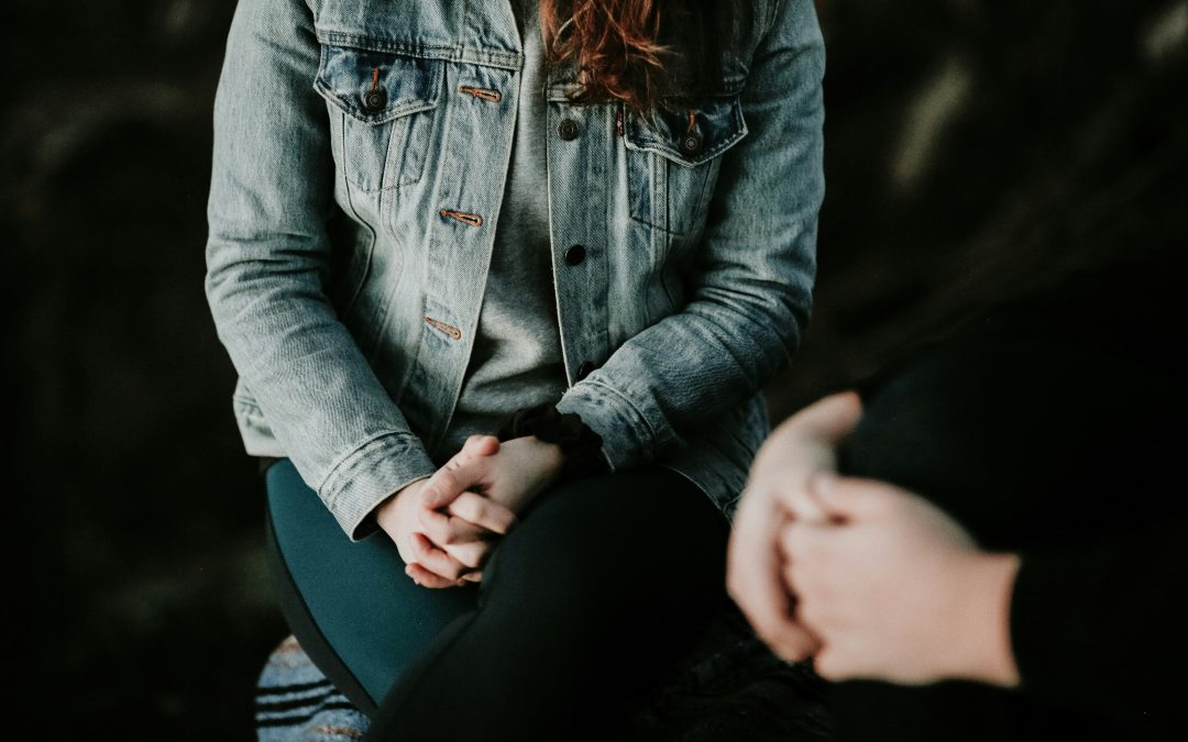 Two people sitting knee-to-knee in a calm therapy conversation, hands clasped, representing EMDR and trauma-focused psychotherapy