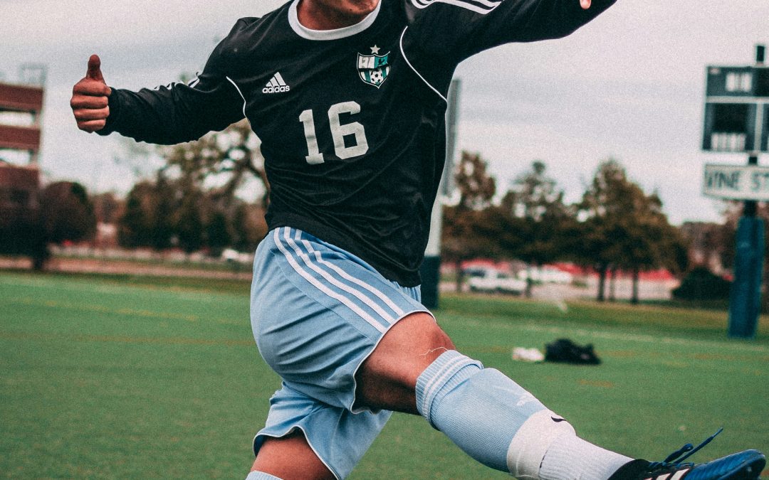 Teen soccer player mid-kick on the field during fall sports season