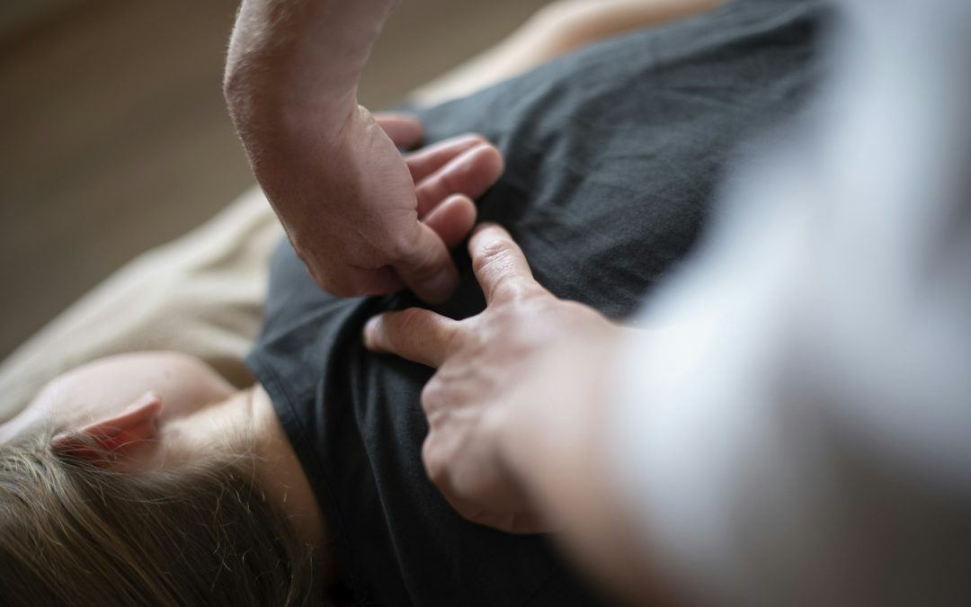 Close-up of hands performing gentle manual osteopathic treatment on a patient's torso