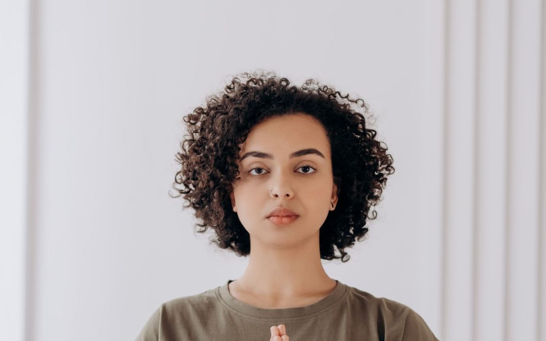 Woman sitting calmly with hands in a meditative gesture, representing healthy boundaries and managing anxiety