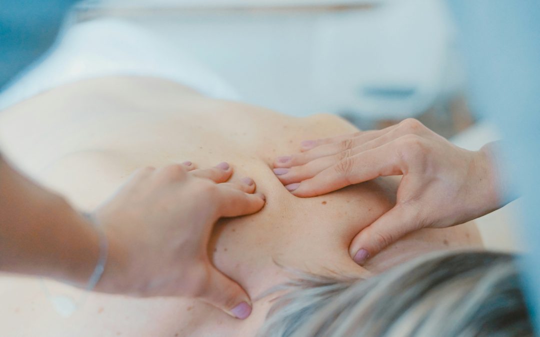 Massage therapist applying moderate pressure to a client's upper back and shoulders during a stress-relief massage session