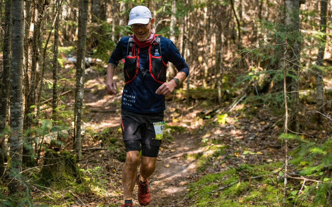 Runner on a wooded trail wearing a race bib during a fall trail race, representing manual osteopathy support for runners