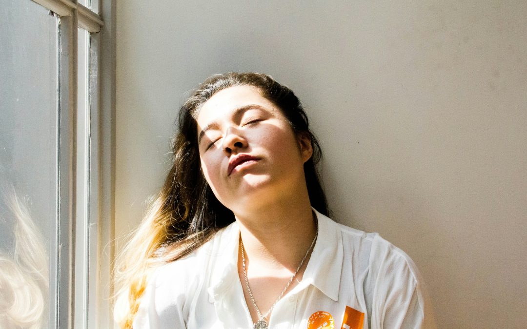 Woman resting peacefully in warm sunlight by a window, reflecting the low energy and fatigue that can come with iron deficiency