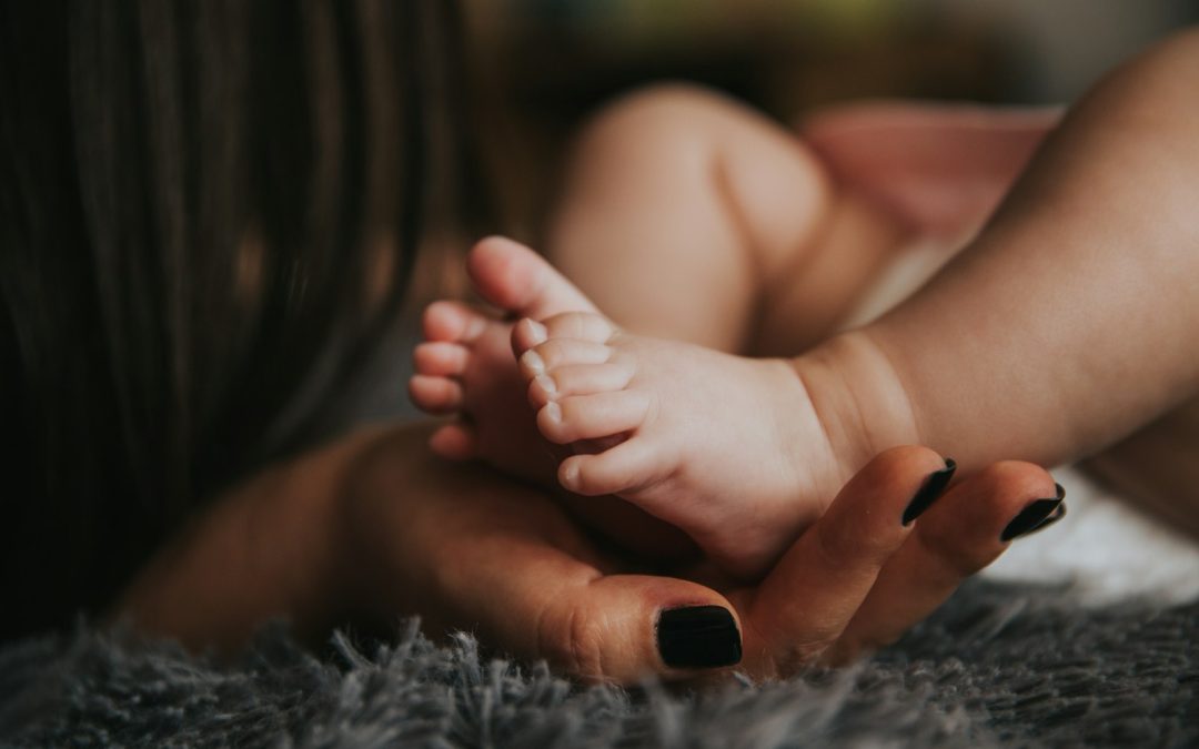 A parent gently holding a baby's feet, representing gentle osteopathic care for infants